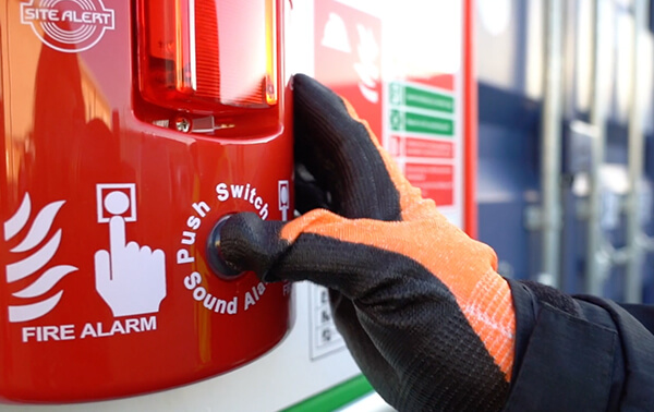 worker pushing button on howler site alert fire alarm